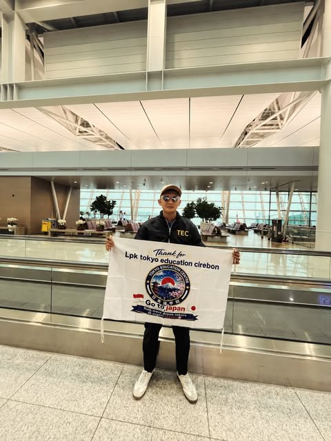 Seseorang membawa banner LPK Tokyo Education Cirebon di terminal